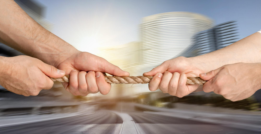 Business people pulling rope in opposite directions at office